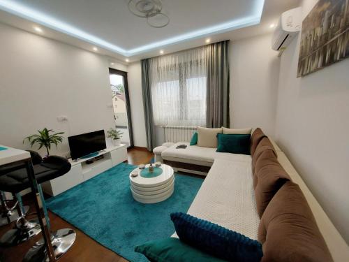 Savremeno uređen enterijer dnevne sobe Duverno Apartment u Novom Sadu sa udobnim kožnim kaučem i dekorativnim jastucima.