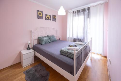 Svetao enterijer Apartment Sunflower021 u Novom Sadu sa romantičnim ružičastim zavesama i francuskim krevetom.